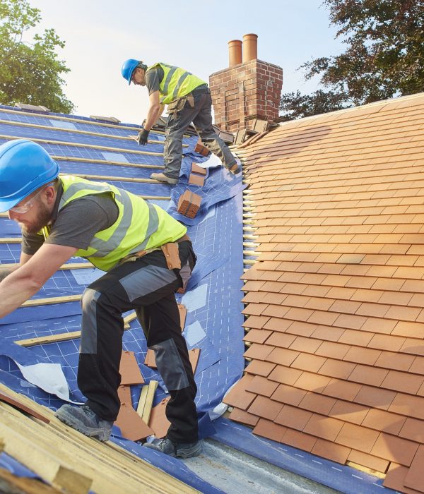 a roofer nails on the roof tiles